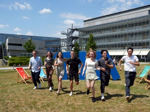 Studierende laufen auf der Campuswiese in einer Reihe Richtung Kamera