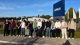 A group of people in front of an airplane and the Airbus company sign.