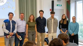 Seven people stand next to each other and look into the camera. 