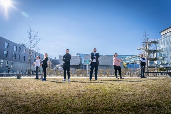 Mehrere Personen mit verschränkten Armen auf der Campuswiese