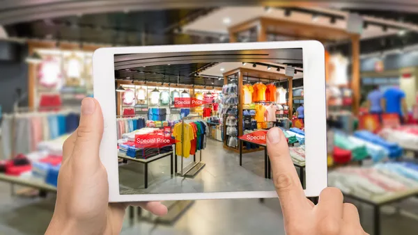 2 hands holding an IPad and taking a photograph of a shop