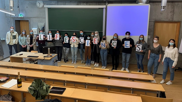 students standing beside each other in front of a lecture hall