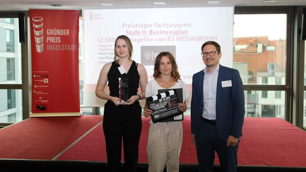 three students in a row, holding the award in their hands