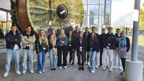 A group of people in front of a giant turbine. 