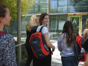 Studentin auf dem Weg Richtung THI Gebäude. Sie lächelt in die Kamera.