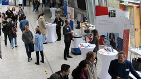 Menschen in einem Foyer und am Messestand